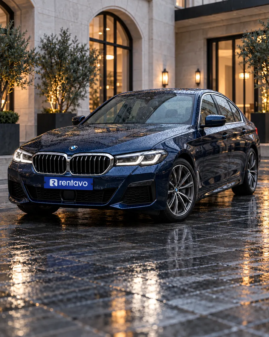 Modré BMW na mokrom chodníku pred hotelom večer