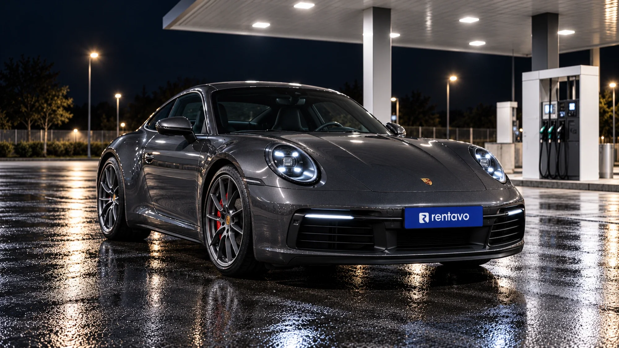 Grafitový Porsche 911 s tabuľkou Rentavo na benzínovej pumpe v noci